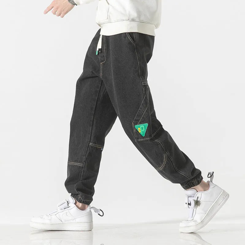 Men's loose-fit tapered cotton trousers in black showing mid-waist design and tapered leg cut