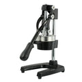 Black manual cast iron citrus juicer with stainless steel funnel on a kitchen counter.