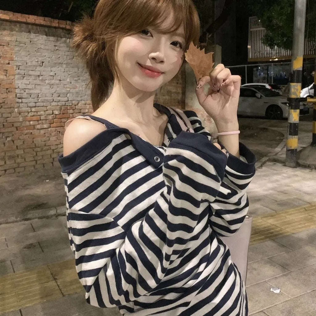 Dark blue oversized women's long-sleeved t-shirt with embroidery, stripes, and button detail on a hanger.