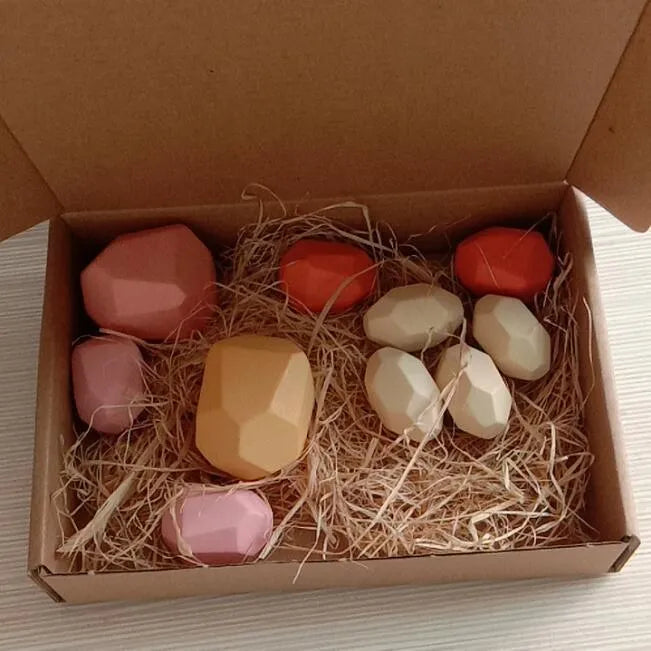 Wooden building block set with coloured and natural stone stacks on a table, suitable for children aged 4-6
