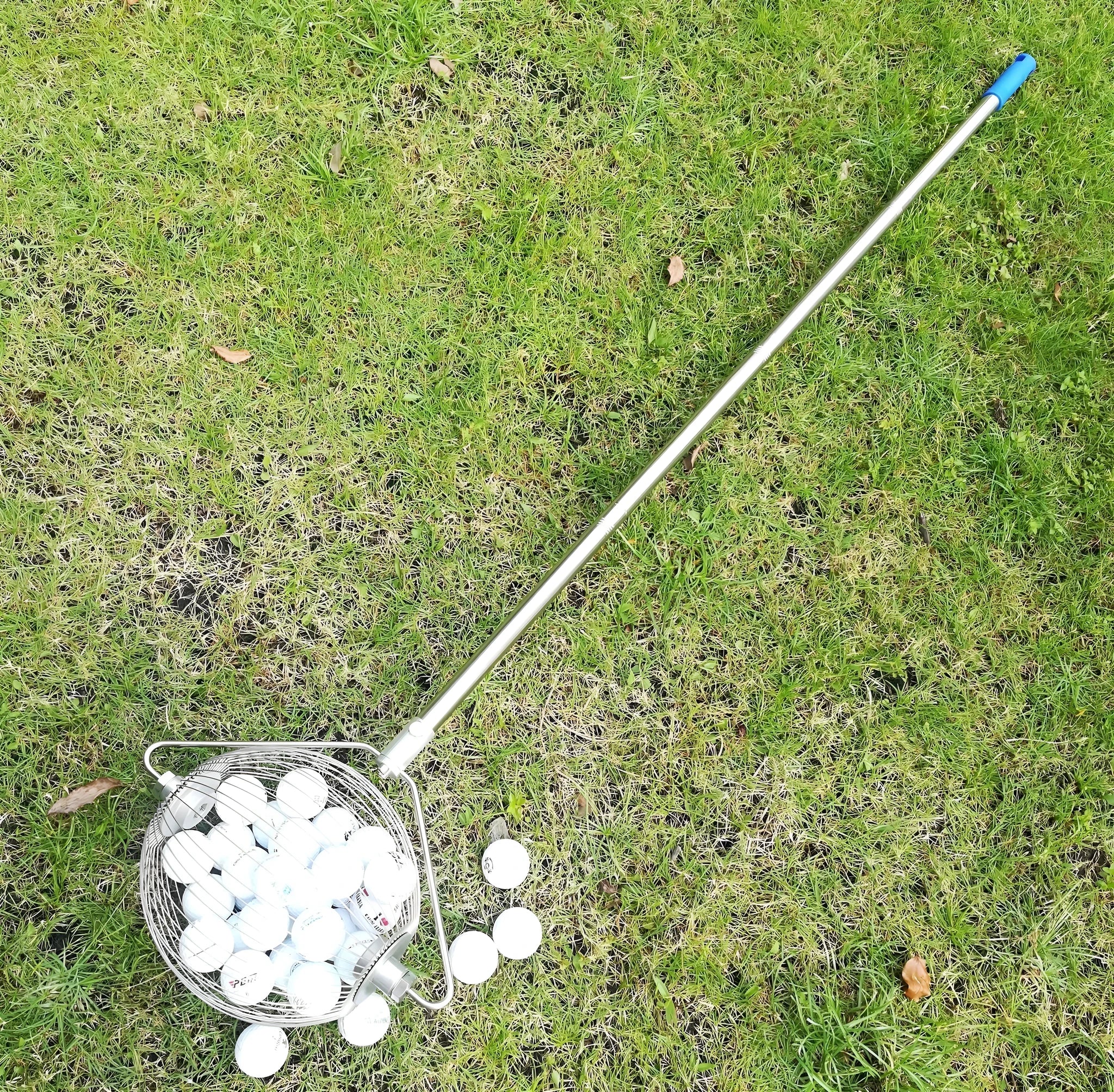 Metallic stainless steel golf ball picker on green grass
