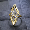 Gold tone women's ring with an exaggerated curved design on a model's finger.