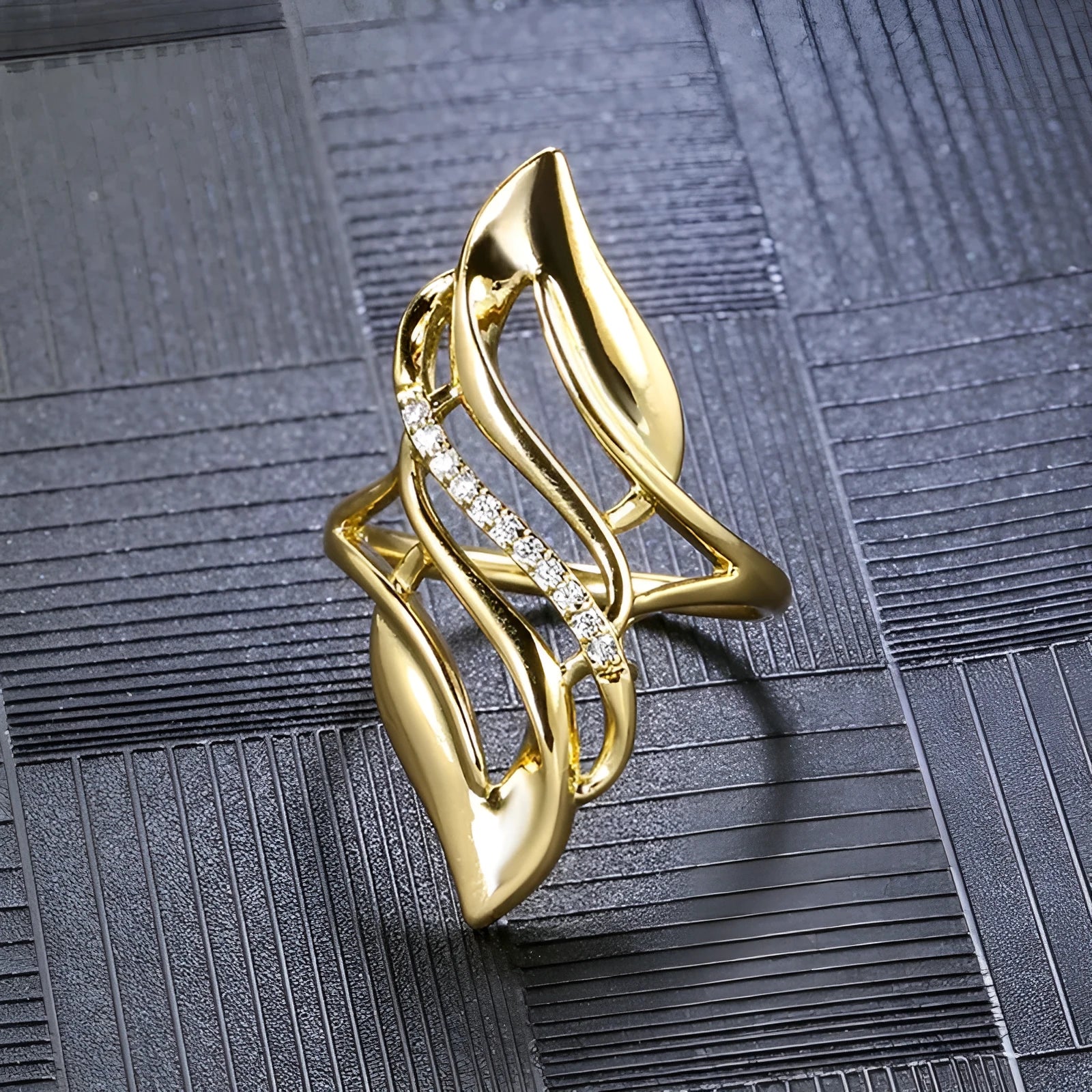 Gold tone women's ring with an exaggerated curved design on a model's finger.