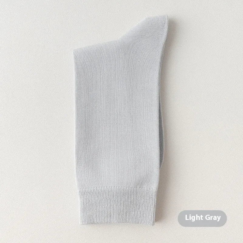 Five pairs of men's solid colour mid-calf socks made from combed cotton, shown in assorted shades.