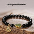 Black obsidian bead bracelet with a carved Hetian jade gourd charm, shown in geometric retro style.