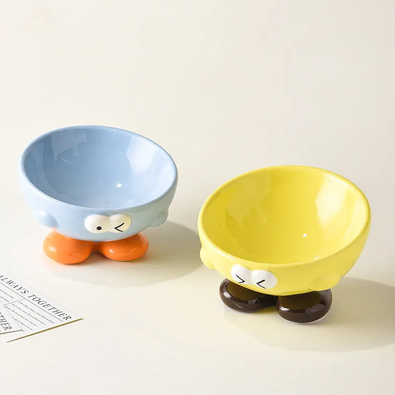 Tall blue ceramic slanted pet bowl with cute expression, designed for cervical spine support.