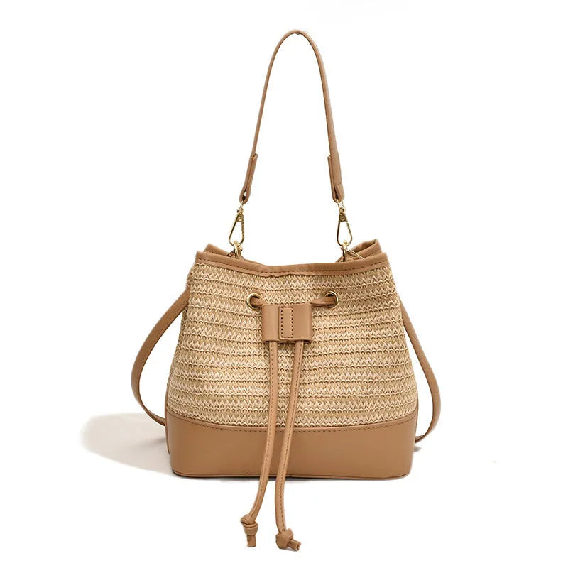 Brown woven straw women's crossbody bucket bag with a long adjustable strap.