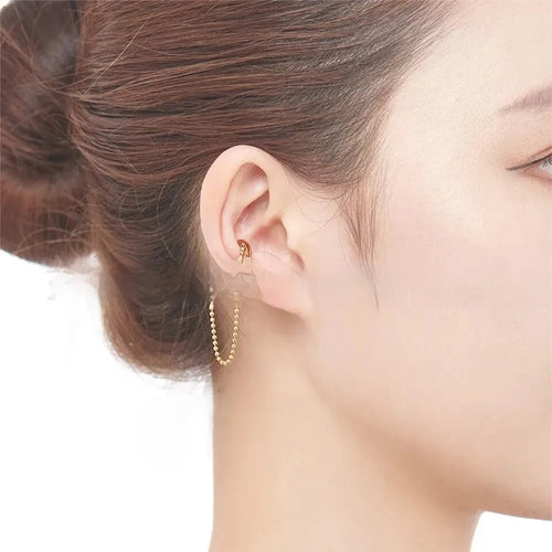 Ball chain tassel ear clip in gold on left ear, copper geometric U-shaped design