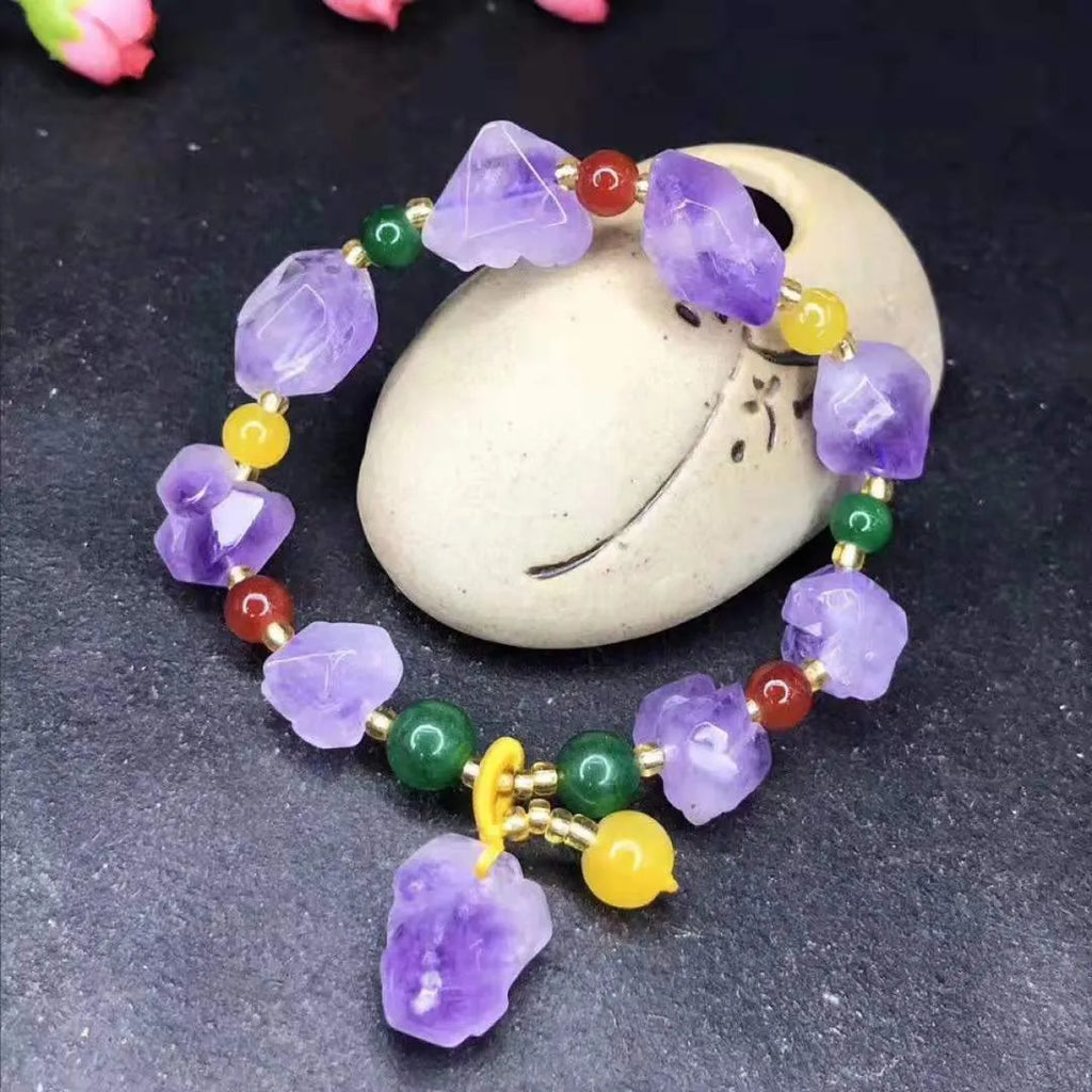 Women's natural amethyst bead bracelet with a fu character charm on a white background.