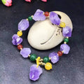 Women's natural amethyst bead bracelet with a fu character charm on a white background.