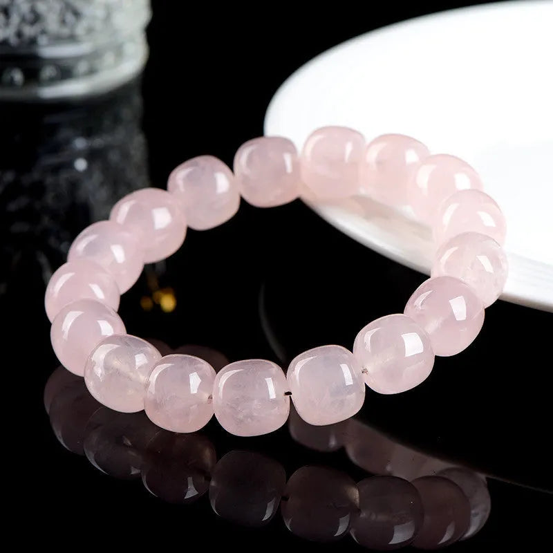 Close-up of a pink geometric bracelet with barrel-shaped crystal beads on a wrist.