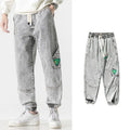 Men's loose-fit tapered cotton trousers in black showing mid-waist design and tapered leg cut