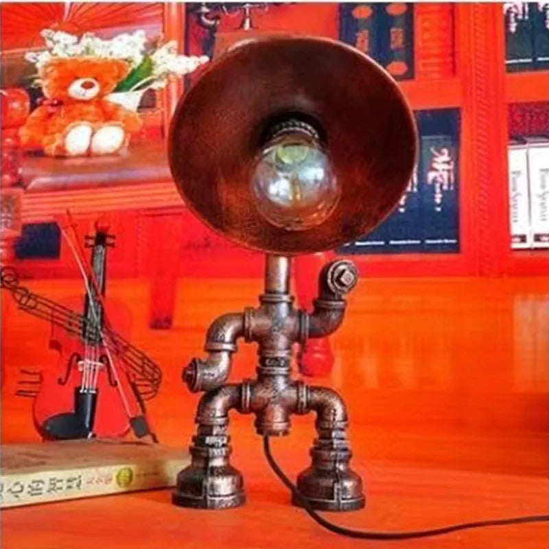 Custom industrial retro style iron pipe robot table lamp on a wooden desk.