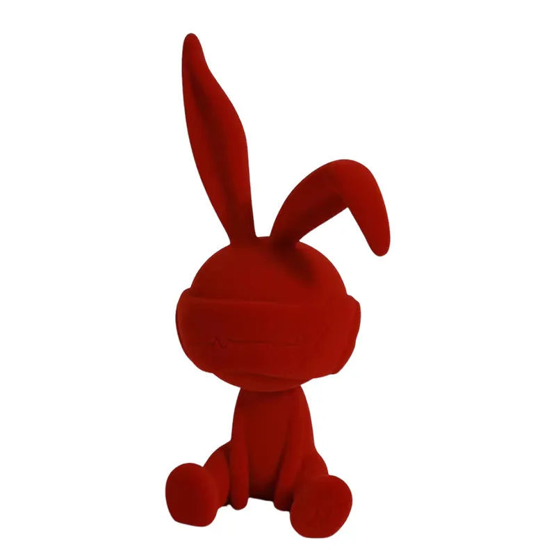 Green resin rabbit table ornament with suede blindfold on wooden surface