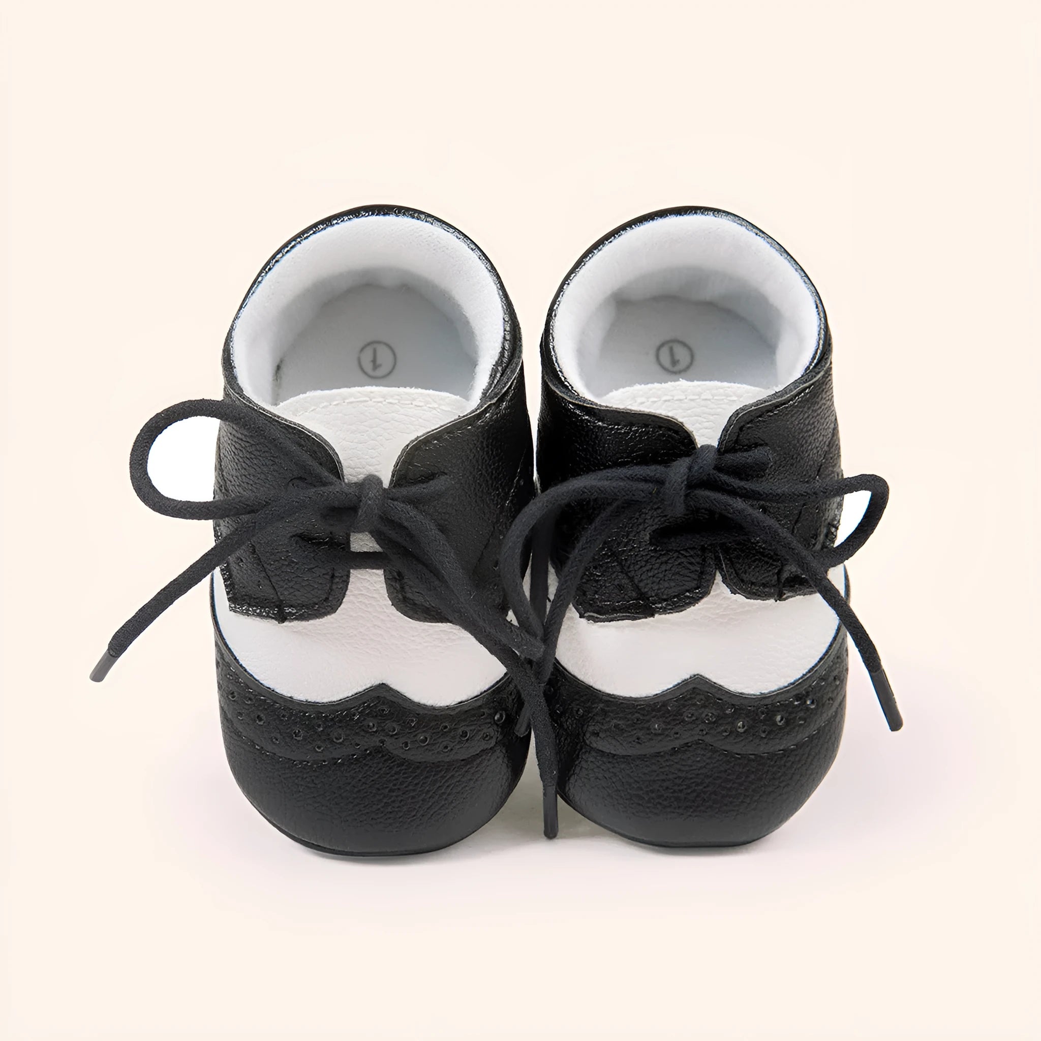 Vintage-style soft-soled baby shoes in black, grey, light brown, and white for infants 0-12 months.