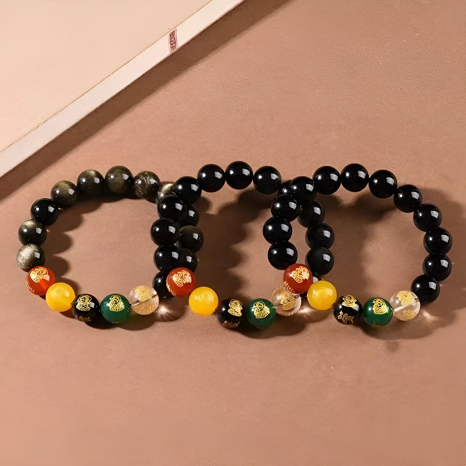 Close-up of a polished crystal bracelet with rainbow eye obsidian beads in a single circle design on a wrist.