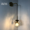 Modern glass wall mounted bedside lamp in golden flower finish on a white wall.