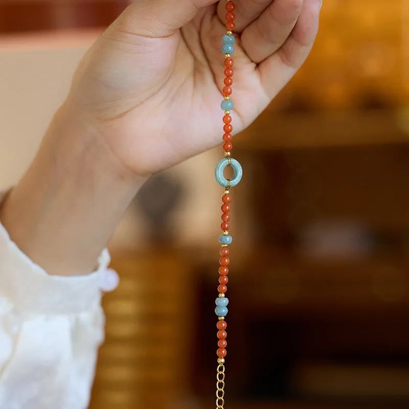 A woman's adjustable South Red Agate bracelet with 4mm beads and a safety buckle on a wrist.