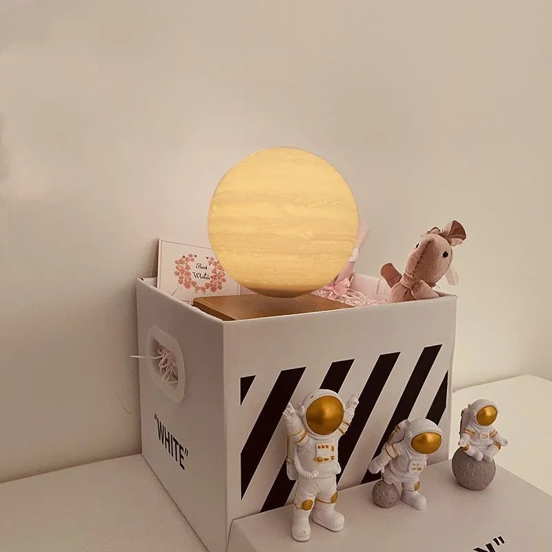 Moon planet floating LED night light with three astronaut figurines on dark surface