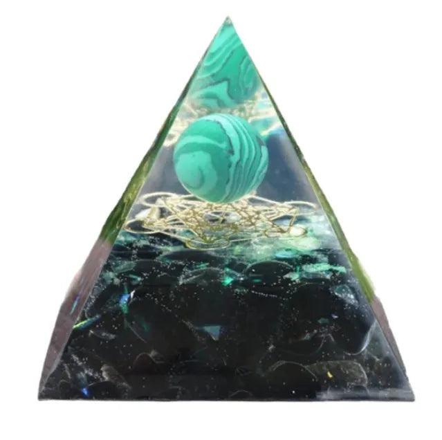 Clear epoxy resin pyramid ornament with natural crystal gravel inside on a wooden surface.