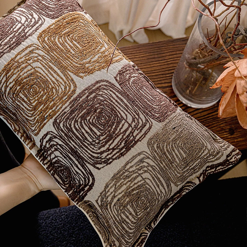 Square cream and coffee abstract coil pattern cushion cover on a grey sofa