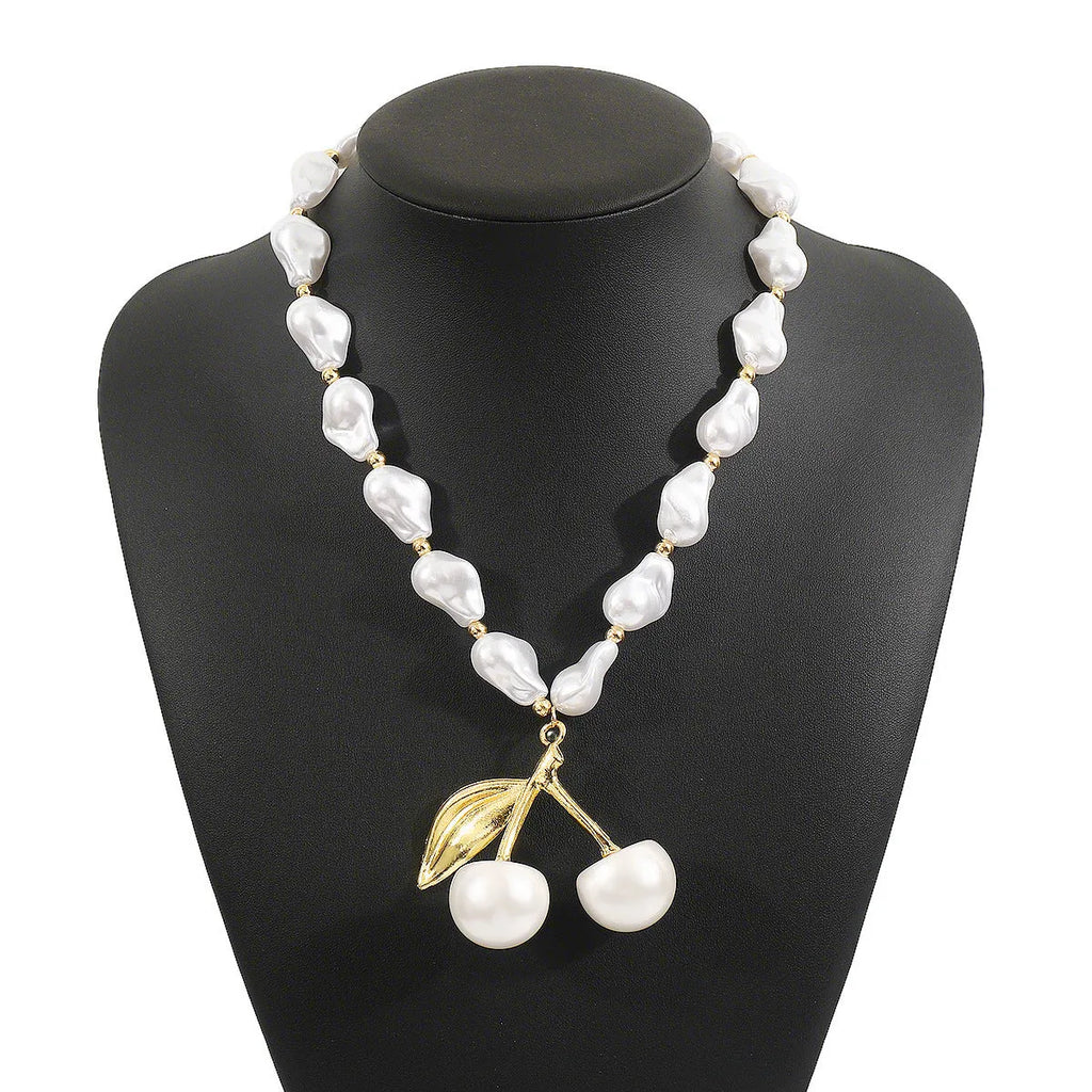 Gold fruit and geometric pendant necklace on a pearl chain, adjustable 51-60cm length.