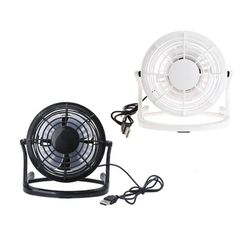 Small black USB desk fan with adjustable tilt on a wooden desk next to a laptop