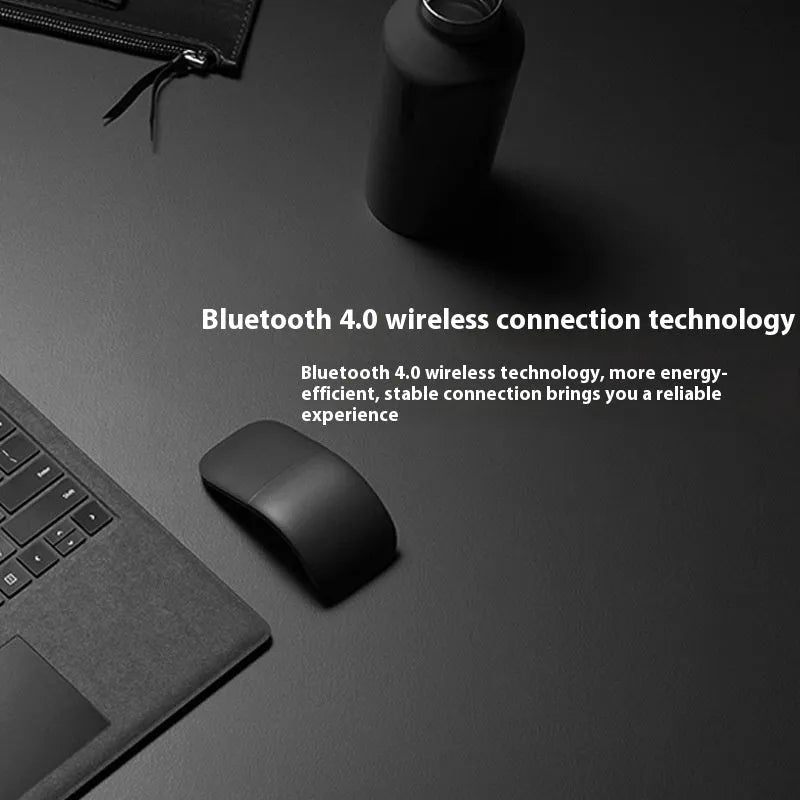 Black folding Bluetooth wireless mouse shown both folded and unfolded beside laptop
