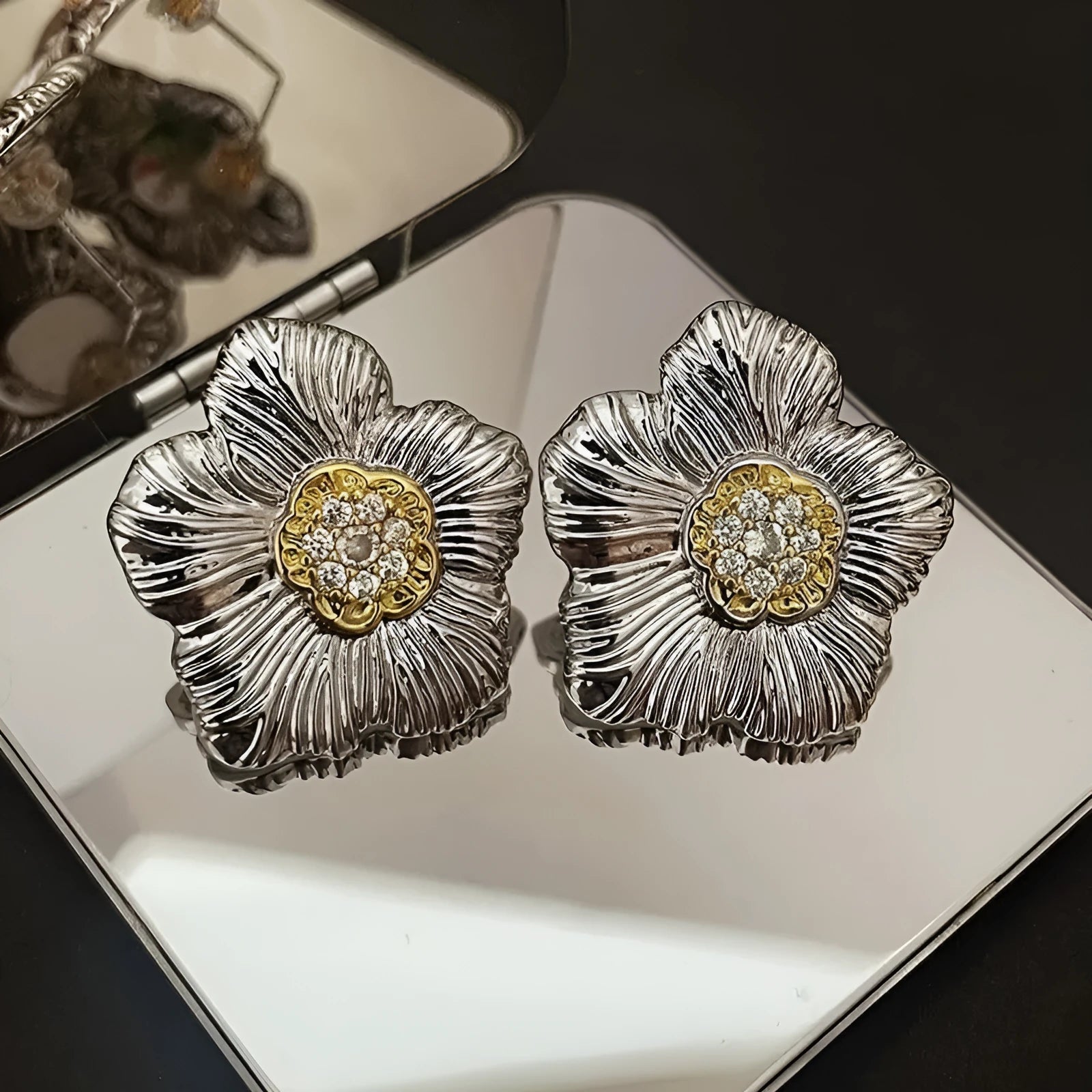 Close-up of women's copper stud earrings with a textured floral design in a two-tone colour.