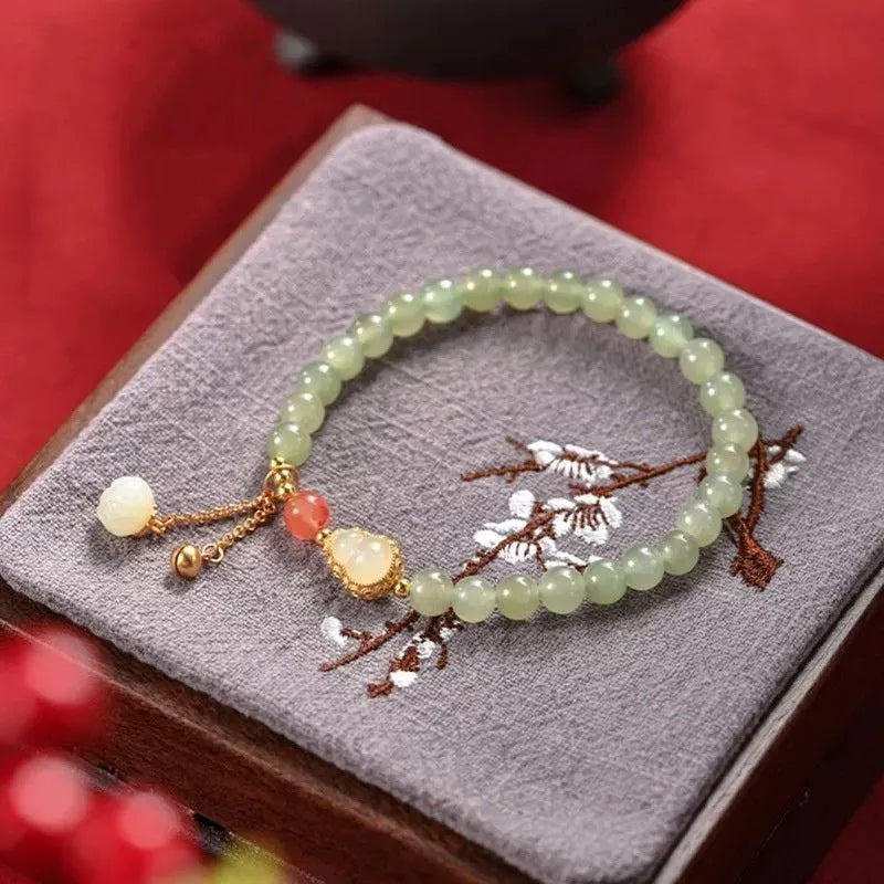 Women's jade bracelet with gold-plated gourd charm and Fu character pendant on a 6mm bead.