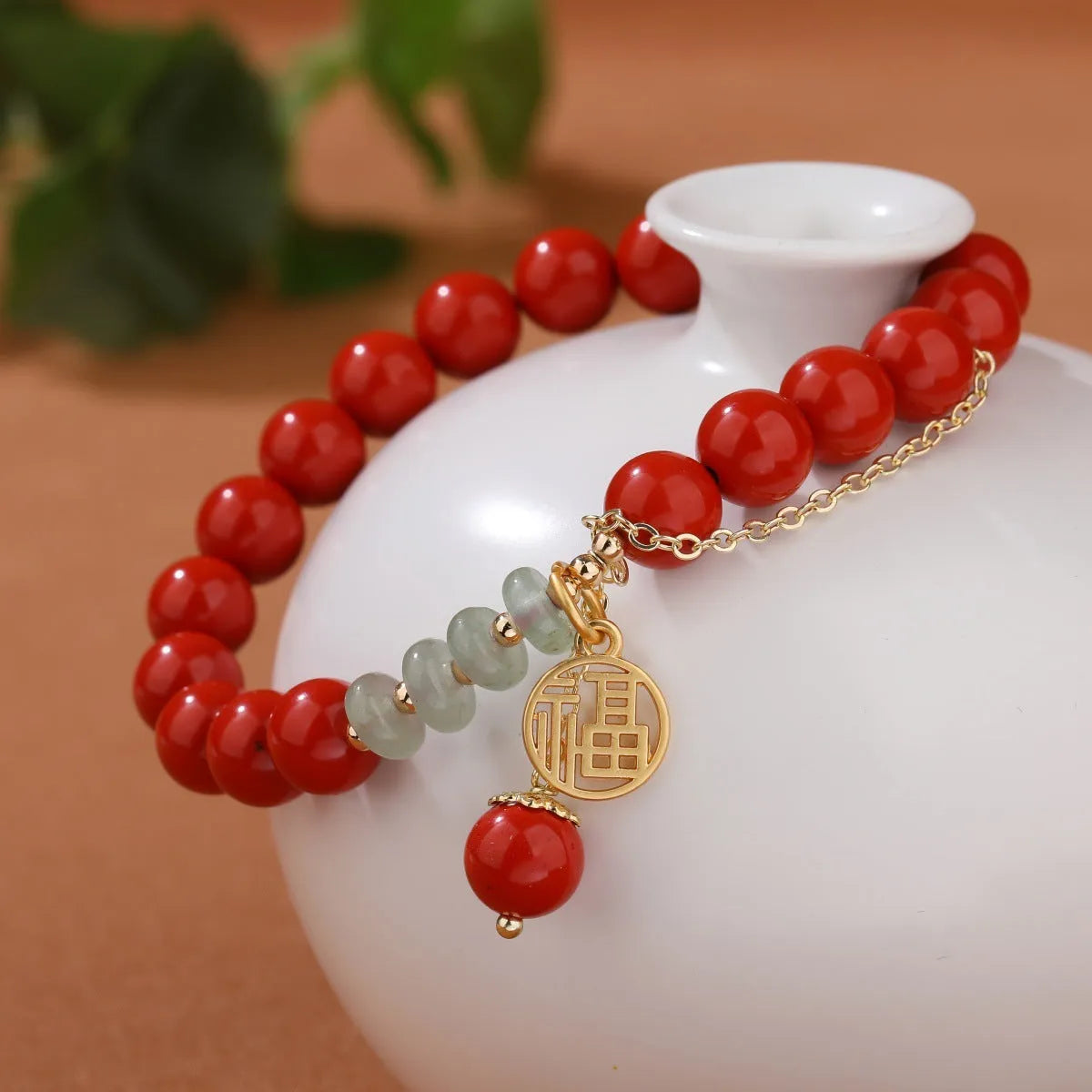 Close-up of a red cinnabar women's bracelet with a Fu character, jade spacer beads, and a small red tassel.