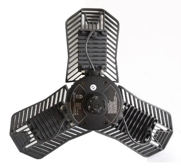 A foldable silver industrial LED garage lamp with a polycarbonate lens, shown in a workshop setting.