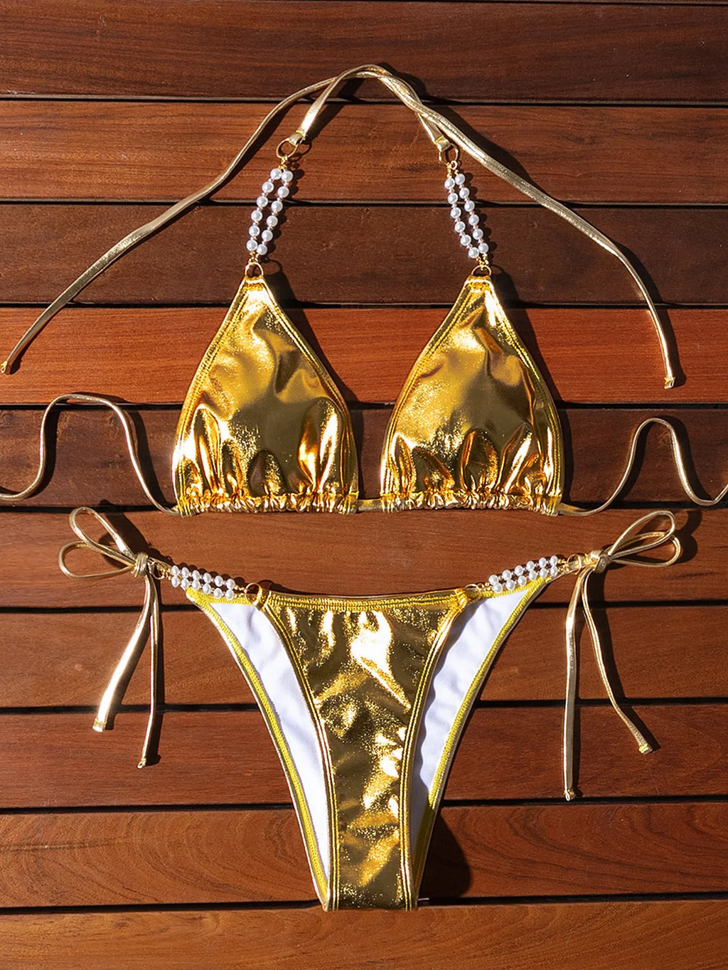 Gold halter lace-up bikini swimsuit with pearl chain detailing on mannequin