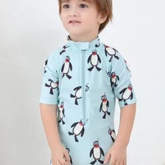 Boys' blue and white penguin print long sleeve swimsuit with matching swimming cap laid flat.