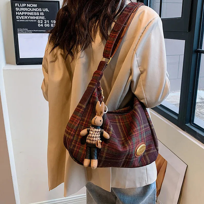 Red women's large wool shoulder bag with pendant on a table, showing square shape and sewing detail.