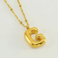 Gold bubble letter N pendant on stainless steel clip beads chain necklace against white background