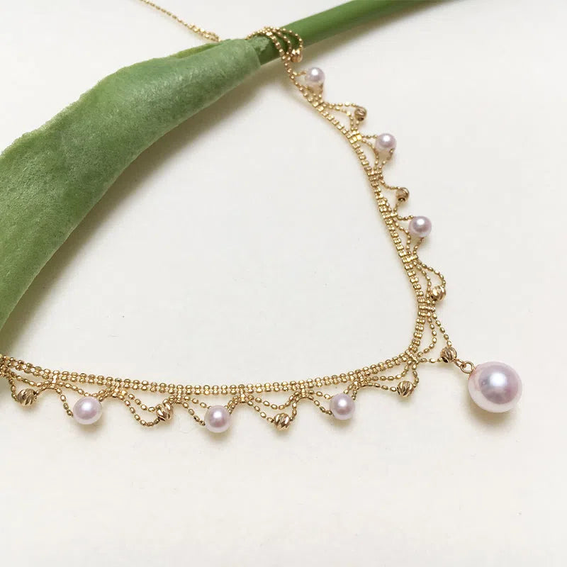 Aurora Japanese 18k gold lace pearl necklace with round sea pearl and gold finish on display