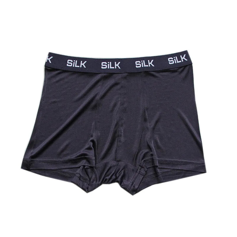 Men's loose-fitting silk shorts in navy blue, shown in a casual setting.