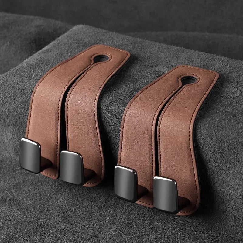 Black suede and metal car seat hook organiser hanging on a car headrest.
