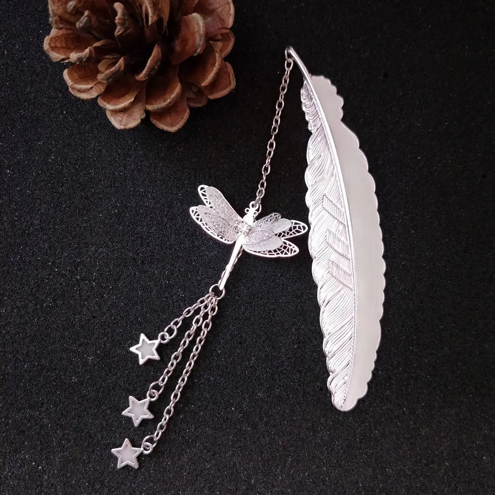 Silver pure copper feather bookmark with glowing luminous butterfly charm on a book.