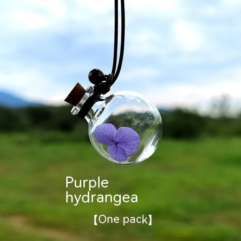 Glass car perfume pendant with preserved flower decoration hanging in car interior