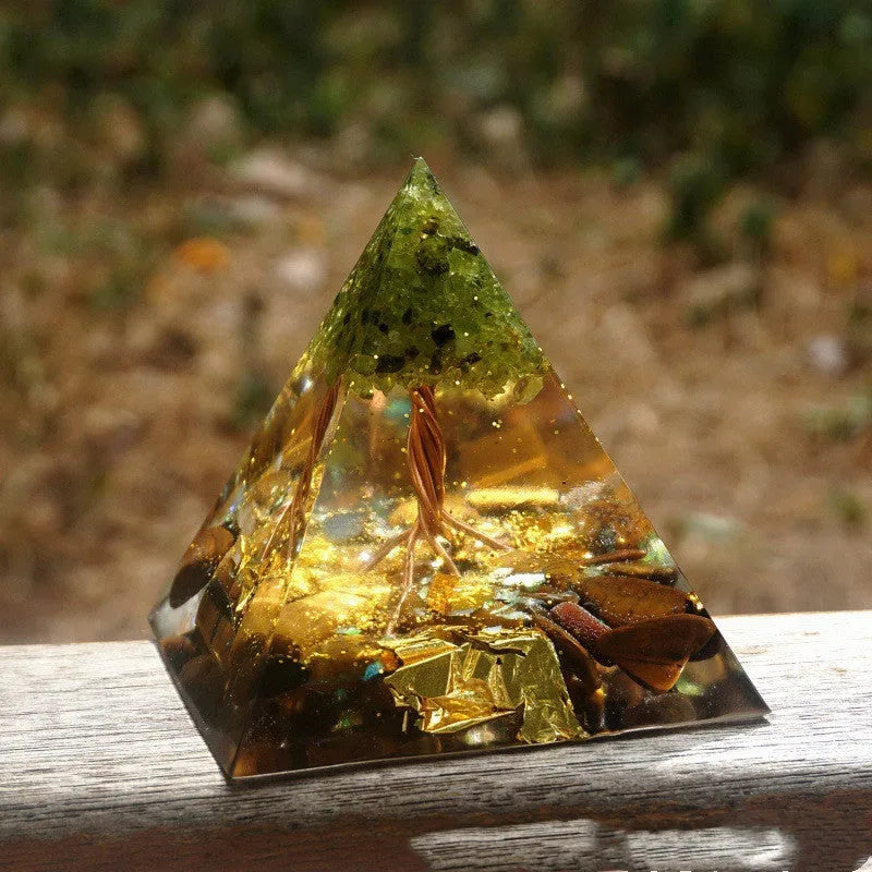 Clear epoxy resin pyramid ornament with natural crystal gravel inside on a wooden surface.