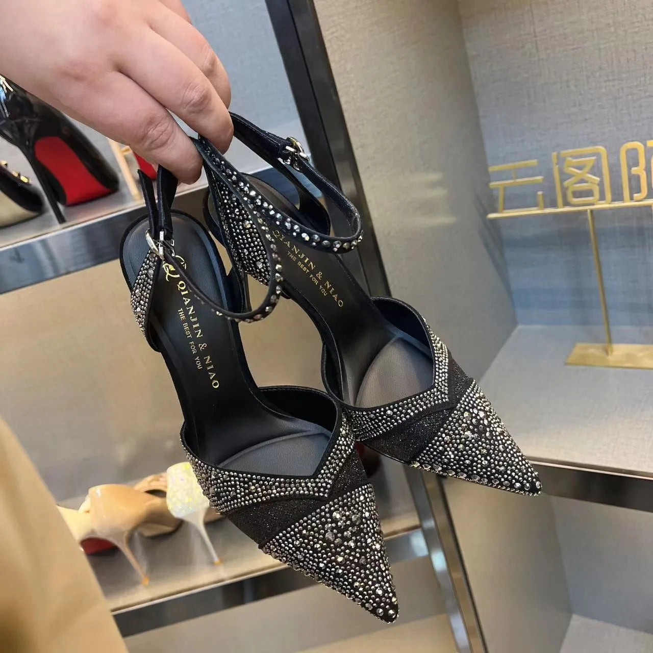Black women's stiletto high heel shoe with a pointed toe and a bright red sole.