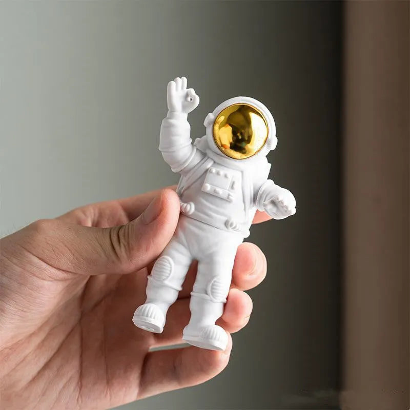 Three resin astronaut figurines for car dashboard decoration, gold finish, placed on dashboard
