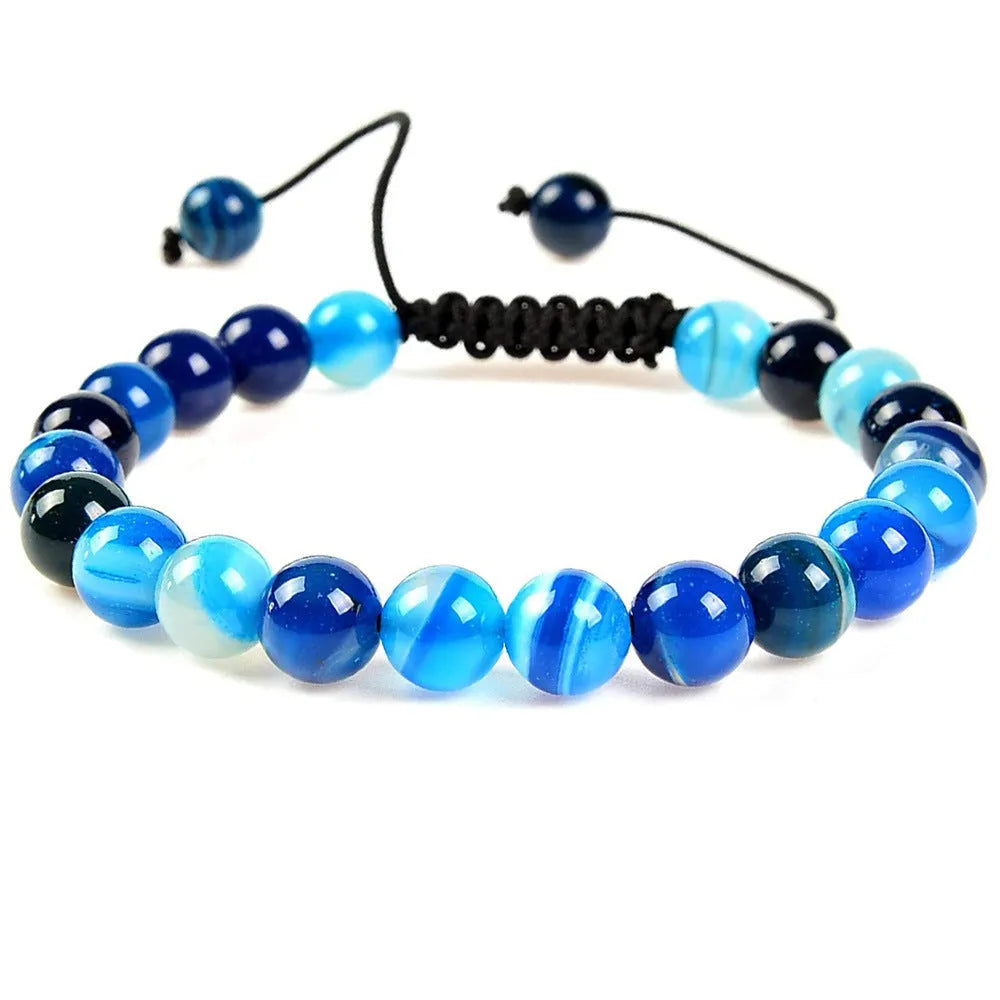 Close-up of a hand-woven flat knot braided bracelet with assorted gemstone beads on a female wrist.