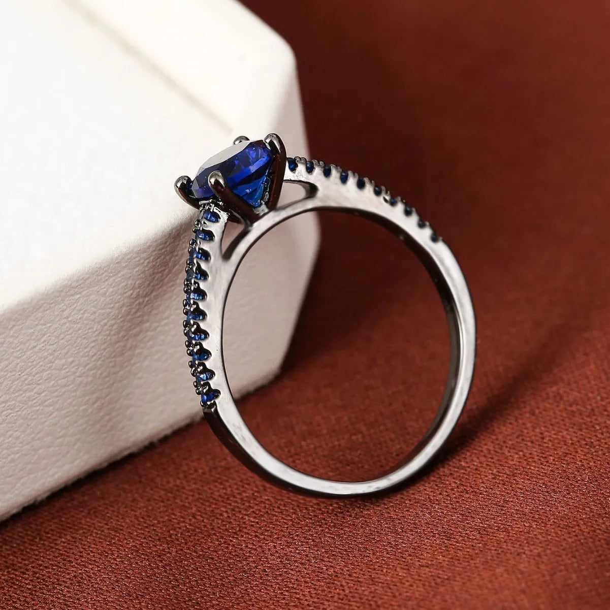 Geometric hexagon zircon ring in copper on a grey background, showing gold rose red and gun black purple colour options.