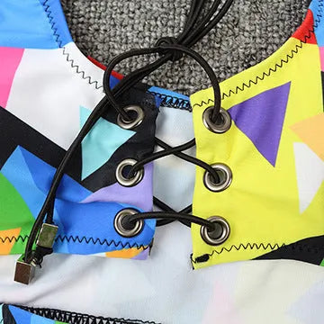 Women's multicolour checkered bikini set with cross-strap bra and high-waist fishnet briefs on a neutral background.
