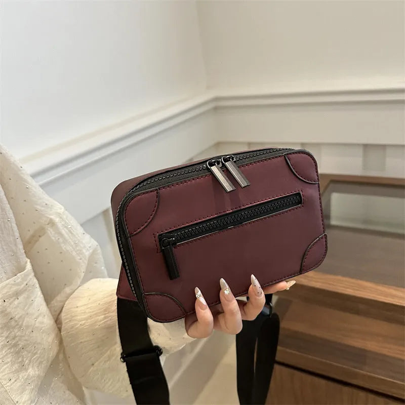 Women's black square crossbody bag showing internal mobile phone pocket and adjustable shoulder strap
