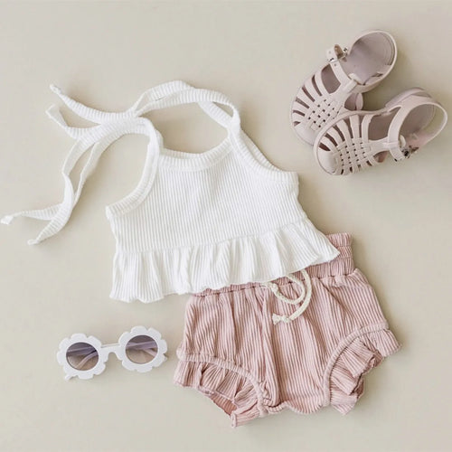Baby girls white knitted cotton vest and pink shorts set on a light background