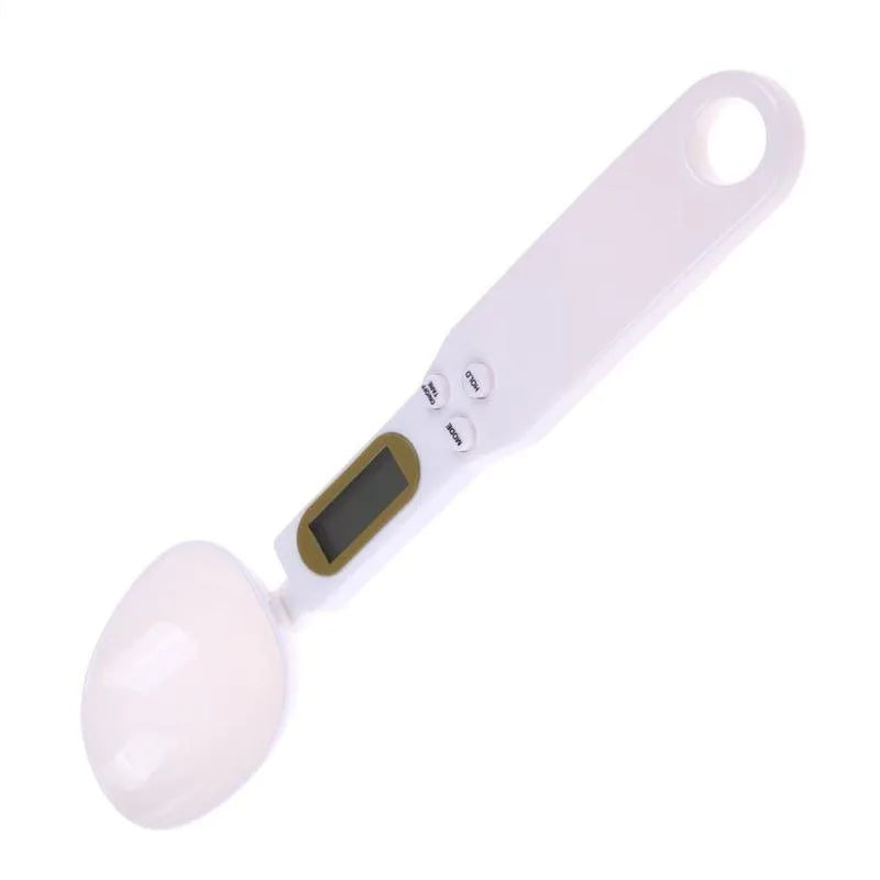 White digital kitchen scale with LCD screen displaying weight, shown next to a measuring spoon.